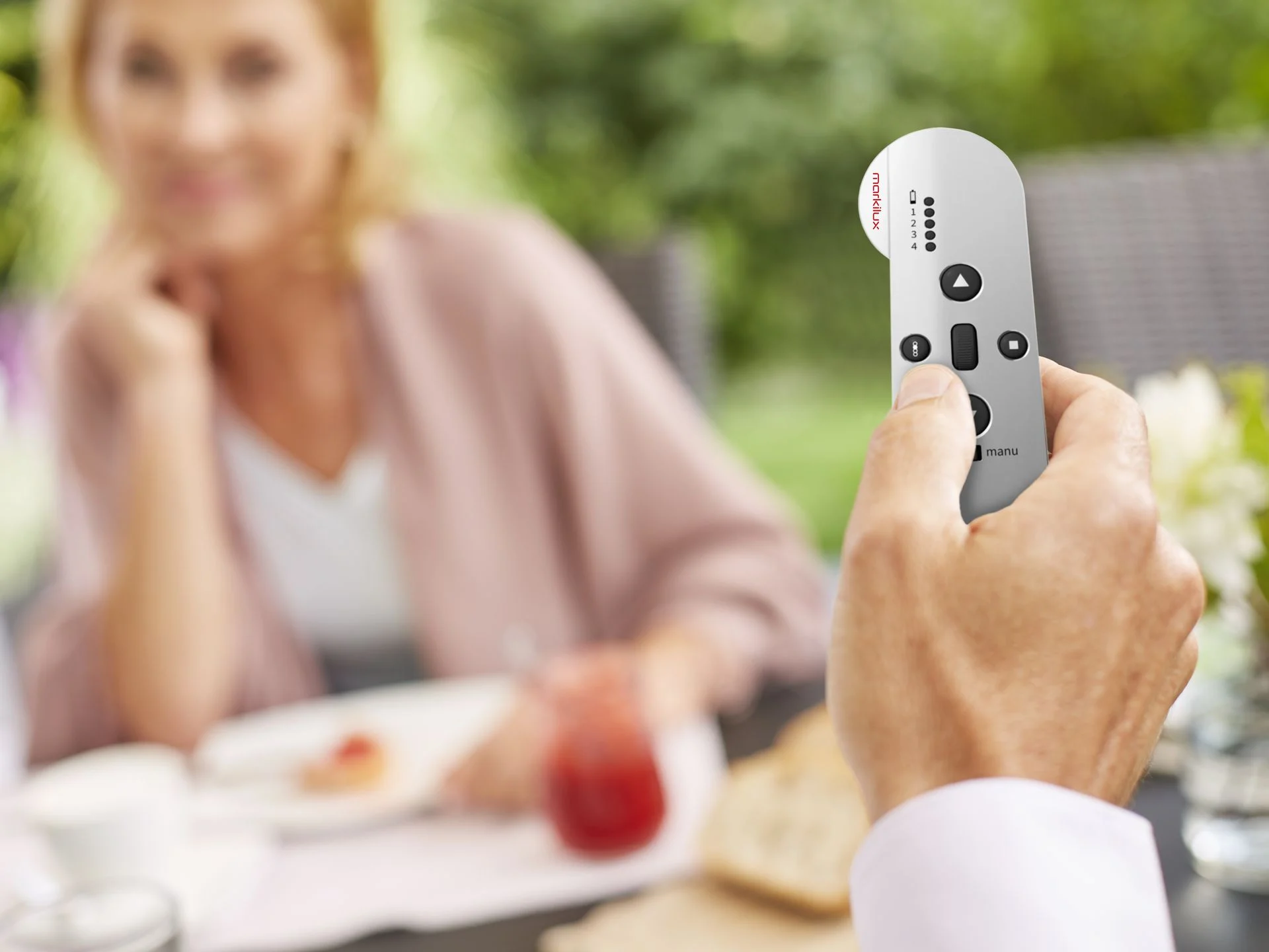 Man Holding Markilux Remote Control At Breakfast Table In The Background - Shade-Space